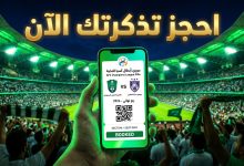 شاشة هاتف تعرض تذكرة مباراة الأهلي وجوهور دار التعظيم في دوري أبطال آسيا مع خلفية لملعب الجوهرة